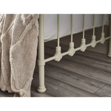 White day bed base with spindle rail trim and curved detailing, with bedding over the side