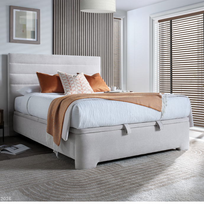 Upholstered ottoman base in light gray fabric with low profile and panel sides