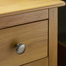 Oak drawer front with round metal knob and visible wood grain