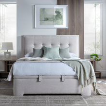 Upholstered ottoman storage bed front view in light gray with tufted headboard and pillows