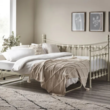 White day bed with spindle headboard and footboard, styled with white bedding and a taupe throw