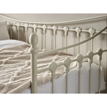 White day bed headboard with turned spindle posts and curved rail, shown with bedding