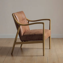 Vintage tan leather armchair, side view with curved back and tapered wood legs