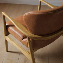 Tan leather armchair detail with curved wooden arm and cushioned seat