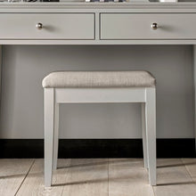 Soft grey upholstered stool with white frame and rounded padded seat