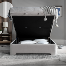 Open light clay ottoman bed showing dark interior and hinged storage lid