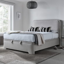 Light clay upholstered ottoman bed with rounded headboard and skirted base
