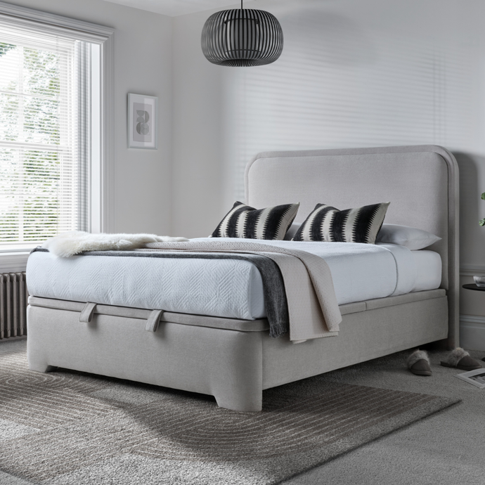 Light clay upholstered ottoman bed with rounded headboard and skirted base