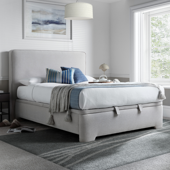 Light gray upholstered ottoman bed with padded headboard and storage base