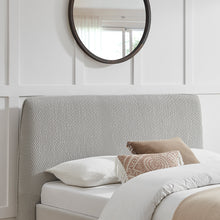 Grey textured upholstered headboard with curved top and neatly styled pillows