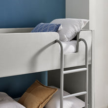 Meadow bunk bed close-up of ladder rails and light gray upholstered headboard.
