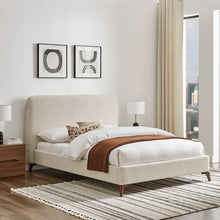 Natural upholstered bedstead with white frame, curved wood legs, and throw blanket