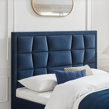 Navy upholstered bedstead with segmented headboard and white bedding with blue throw