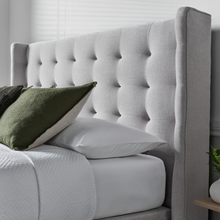 Upholstered ottoman bed side view with tufted backrest and light gray cushion base