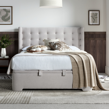 Upholstered ottoman bed with tufted headboard and light gray storage base, pillows on top