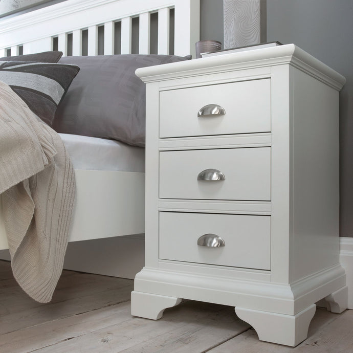 White three-drawer bedside cabinet with arched metal handles and raised panel trim